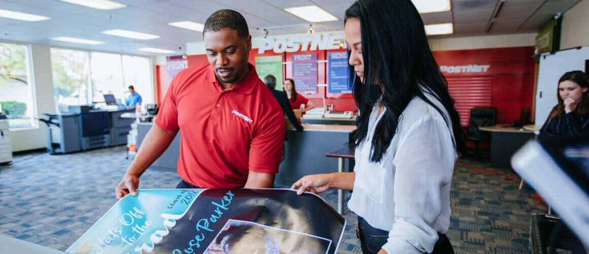 Postnet employee assisting customer with printing. 