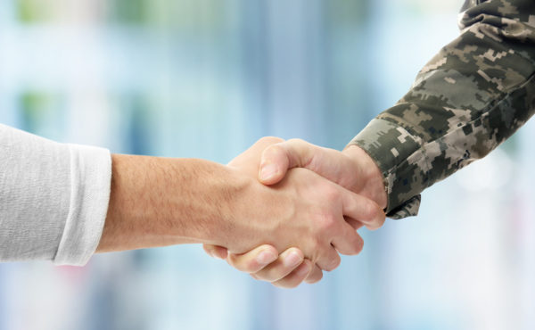 Military Service Member shaking hands with another man. 