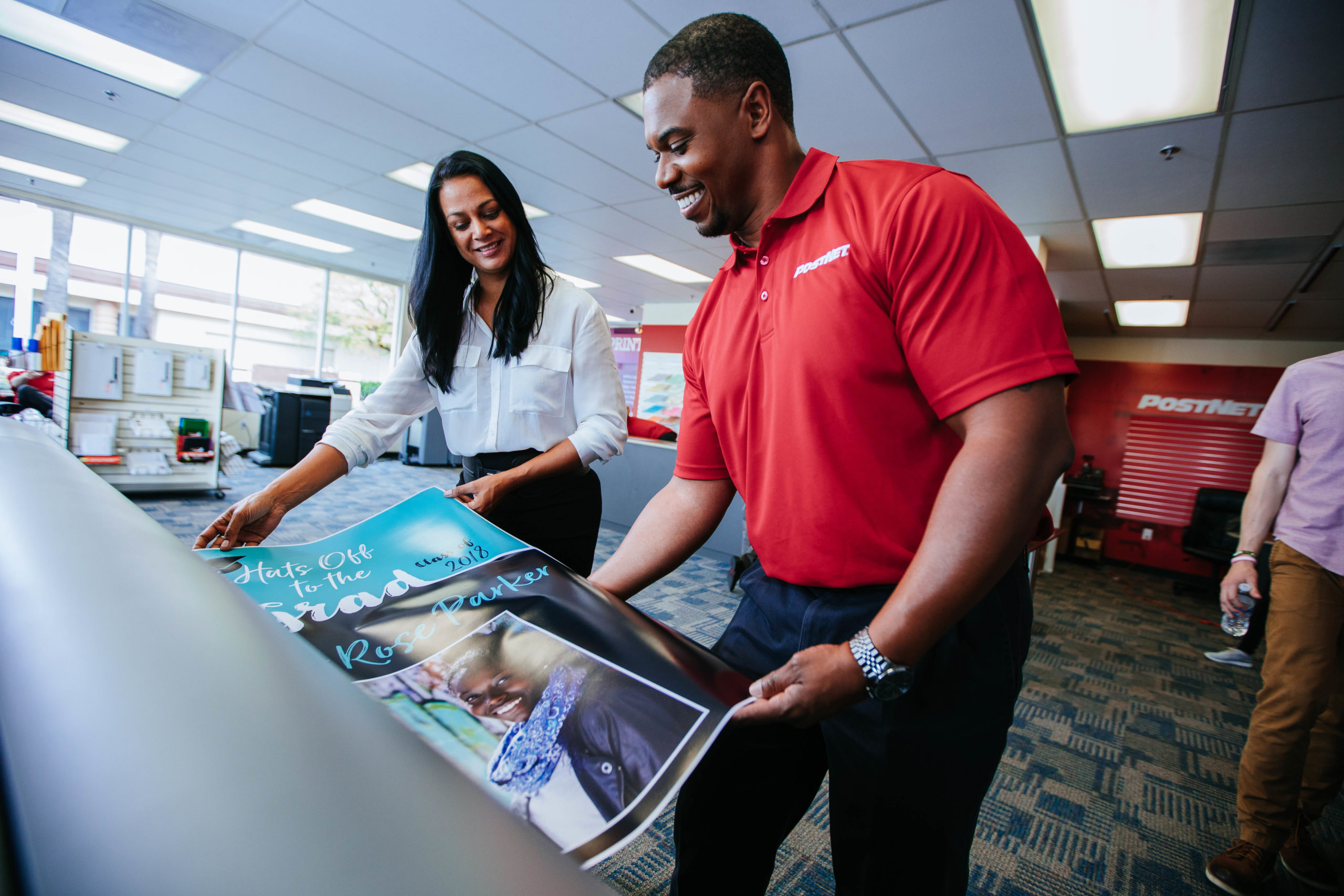 PostNet employee assisting woman with printing