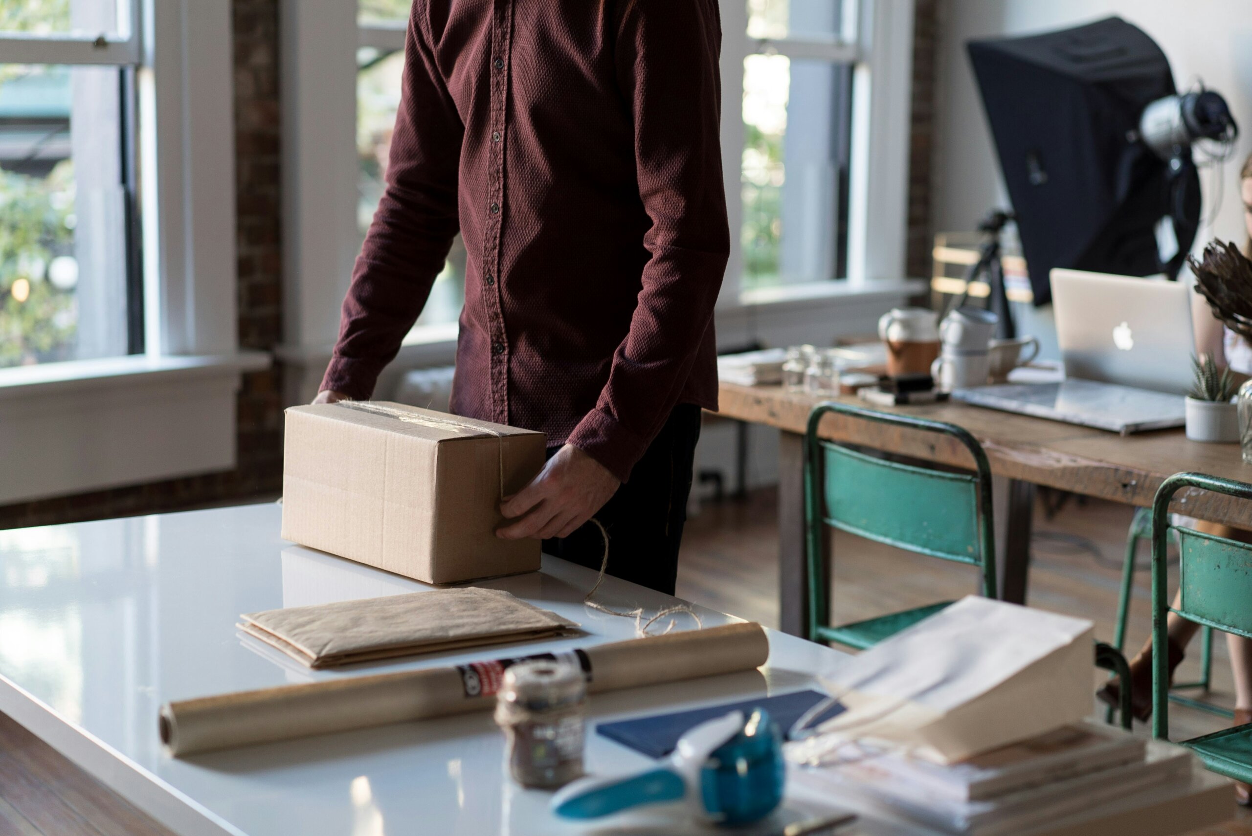 Person in an office, packaging a box on a table.